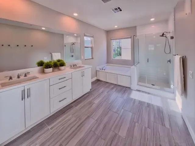 a large bathroom with a double vanity sink a large mirror a bathtub and a shower