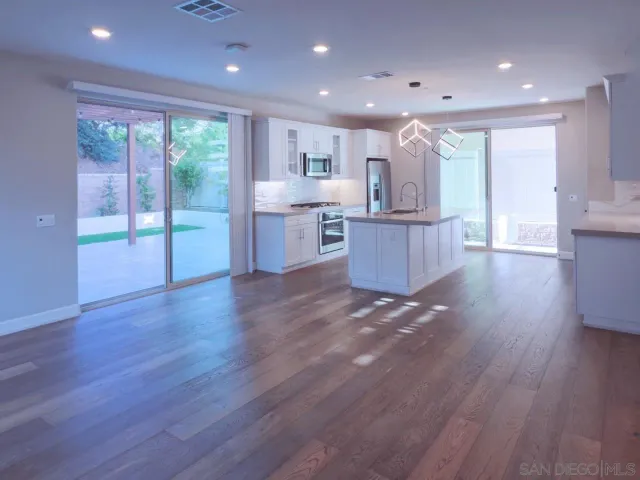 a view of kitchen with kitchen island wooden floors and living room view