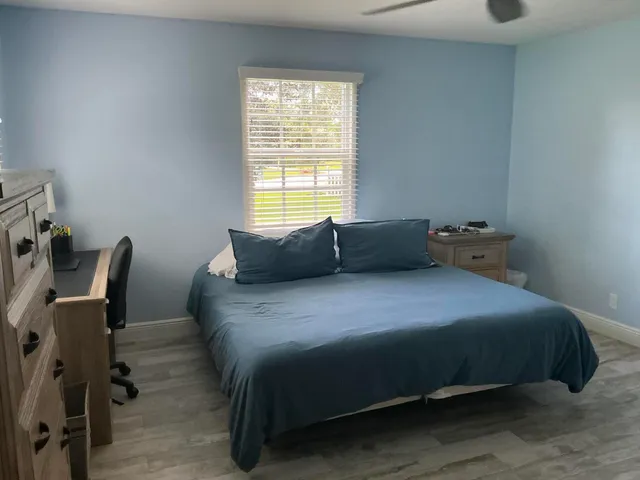 a bedroom with a bed chair and two windows
