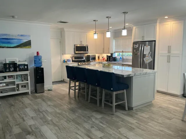 a kitchen with stainless steel appliances a dining table chairs and stove