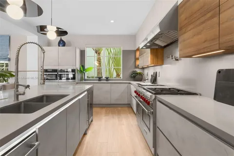 a large kitchen with kitchen island a large counter space a sink appliances and a large window