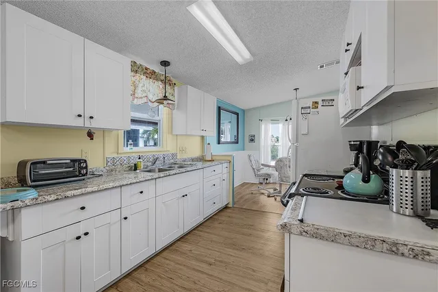 a kitchen with granite countertop a sink a stove and cabinets