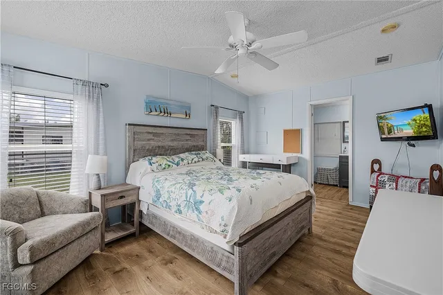 a bedroom with a bed a couch and a flat tv screen