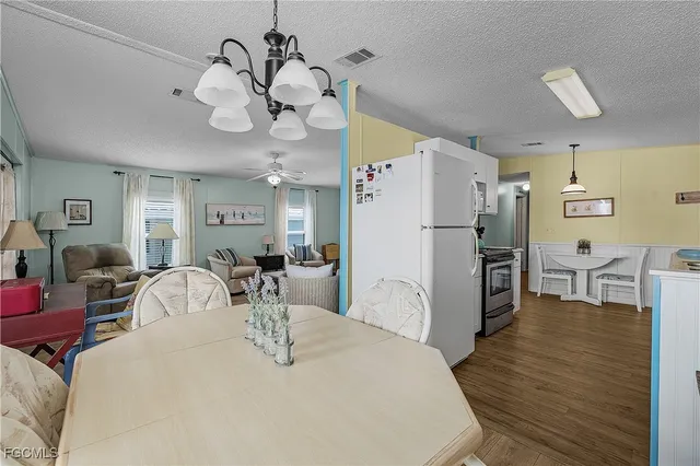 a very nice looking dining room with kitchen island a table and a chandelier