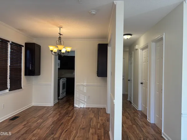 a view of a hallway with wooden floor and a kitchen