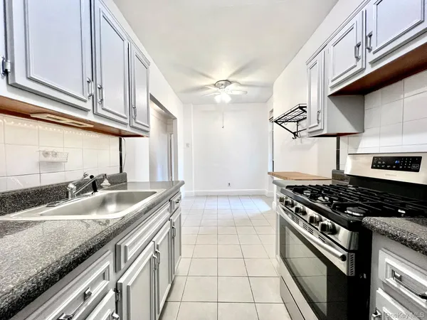 a kitchen with granite countertop a sink a stove and cabinets