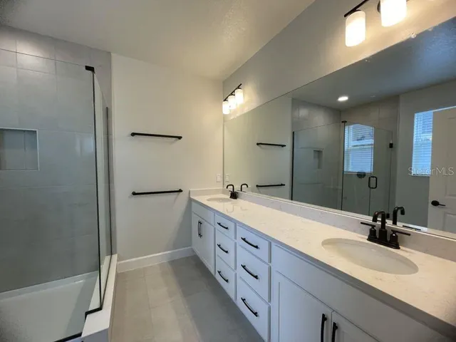 a bathroom with a double vanity sink mirror double and shower