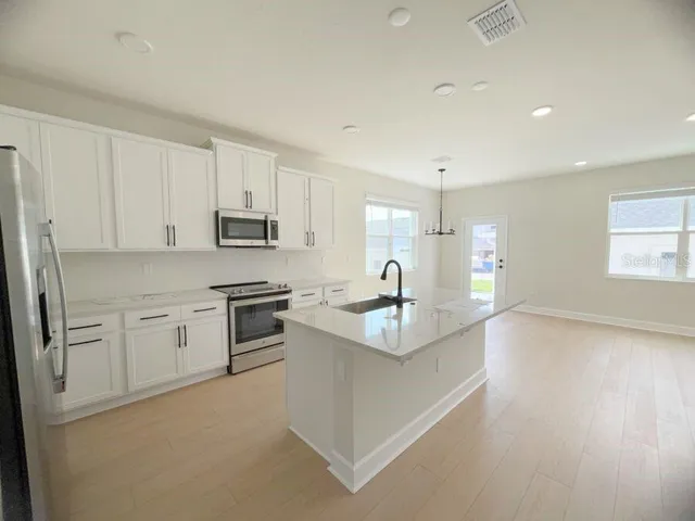 a kitchen with stainless steel appliances granite countertop a sink a stove a refrigerator and cabinets