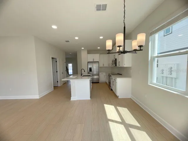 a large kitchen with stainless steel appliances kitchen island a large counter top a stove a chimney a sink and a refrigerator