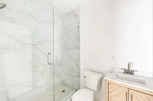 a bathroom with a granite countertop shower a sink and toilet
