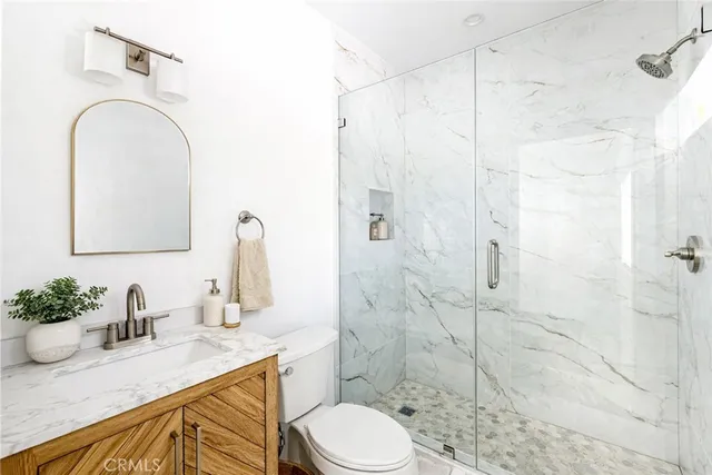 a bathroom with a granite countertop sink a toilet and shower