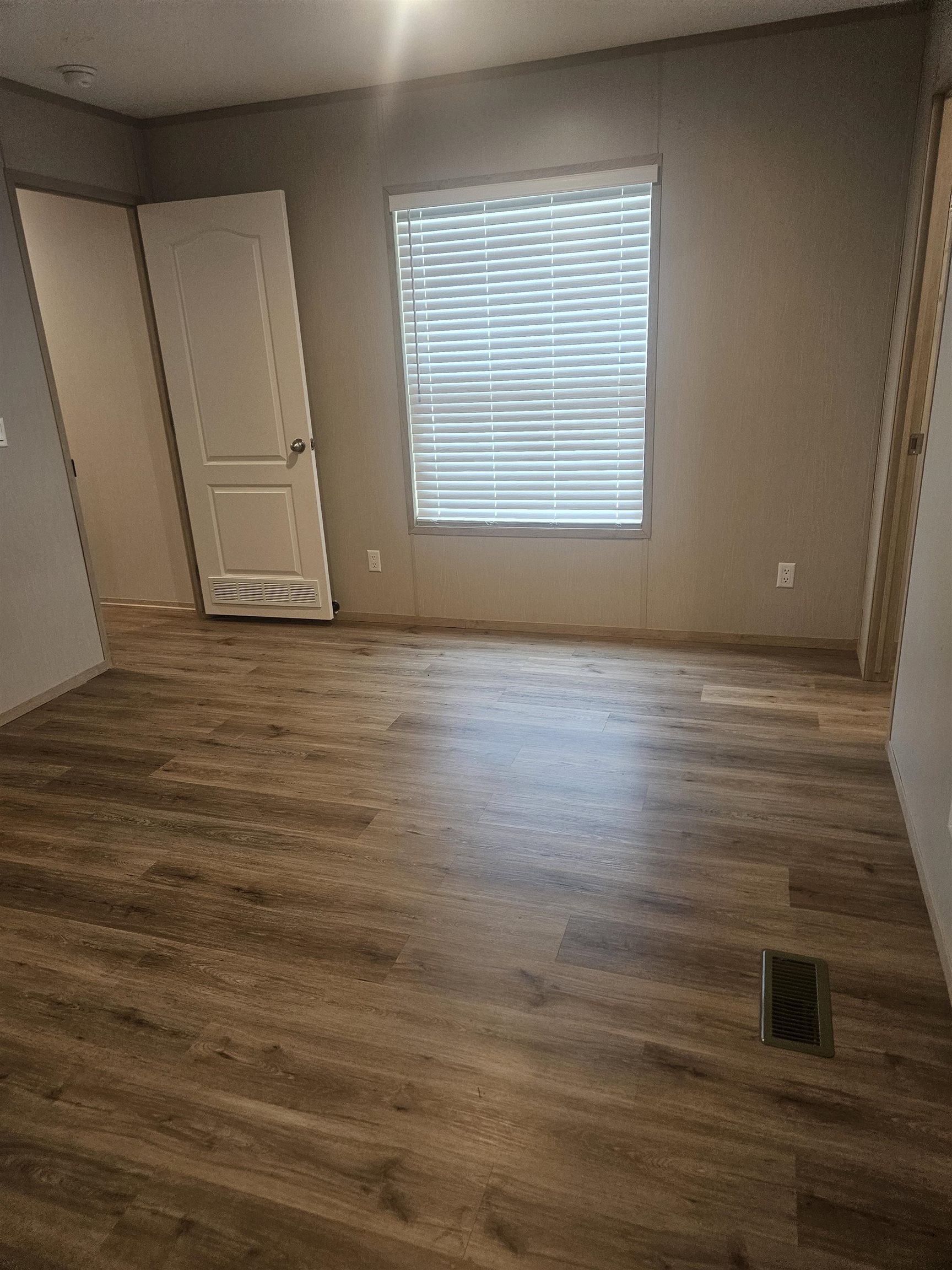 75 Pittman Road, Unit ROAD Somerville, TN 38068 - Photo 16 of 26 Wood-finish flooring throughout, featuring a window with horizontal blinds, neutral wall tones, and white trim