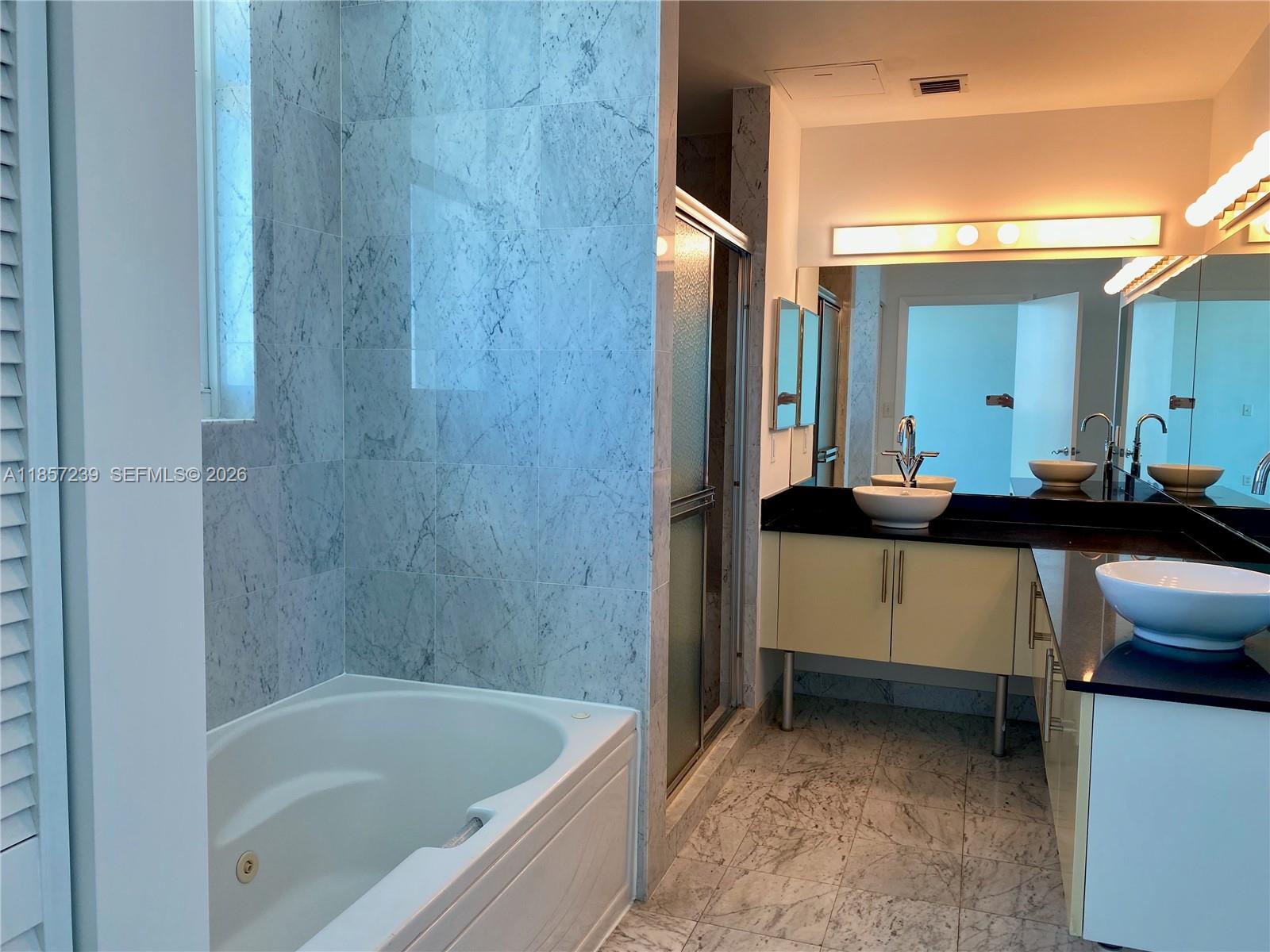 31 Southeast 5th Street, Unit 3912 Miami, FL 33131 - Photo 10 of 13 a bathroom with a bathtub sink and mirror