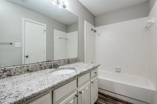 a bathroom with a granite countertop bathtub shower sink and mirror