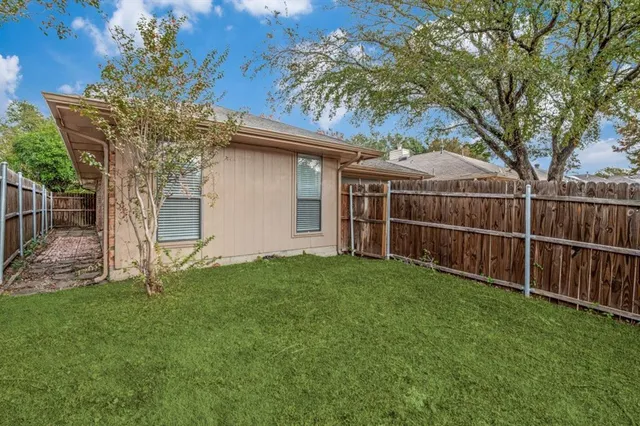 a view of a backyard with plants and large trees