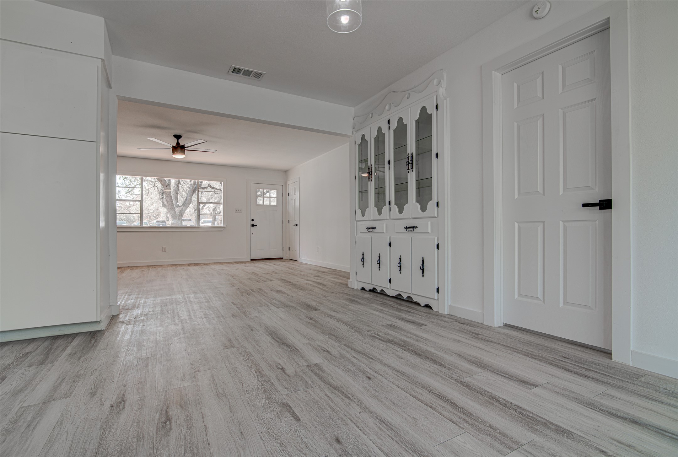 207 Haley Road Johnson City, TX 78636 - Photo 9 of 31 Natural light illuminates the gray wood-look flooring and a functional built-in storage cabinet.