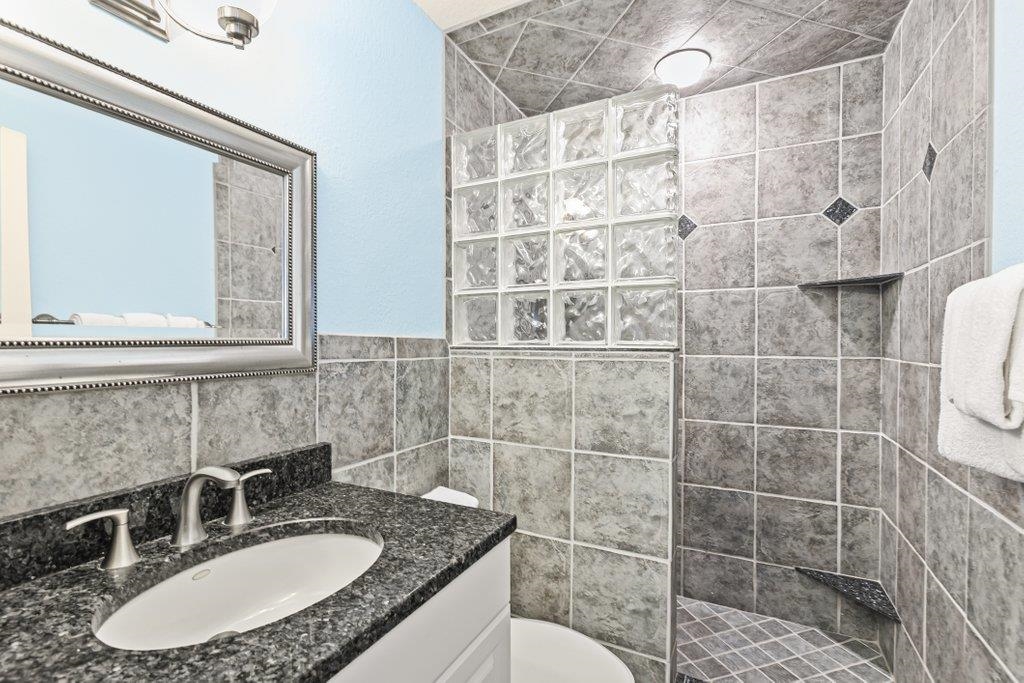 8550 A1A South, Unit 208 St. Augustine, FL 32080 - Photo 34 of 56 a bathroom with a granite countertop sink a mirror and a shower