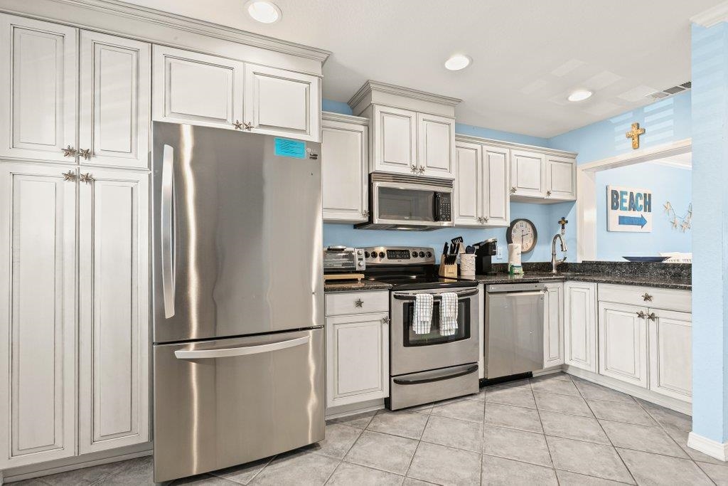 8550 A1A South, Unit 208 St. Augustine, FL 32080 - Photo 9 of 56 a white kitchen with stainless steel appliances granite countertop a refrigerator a stove a sink and white cabinets