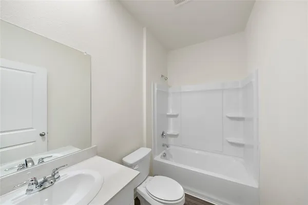 a bathroom with a bathtub shower sink vanity mirror and toilet and a sink