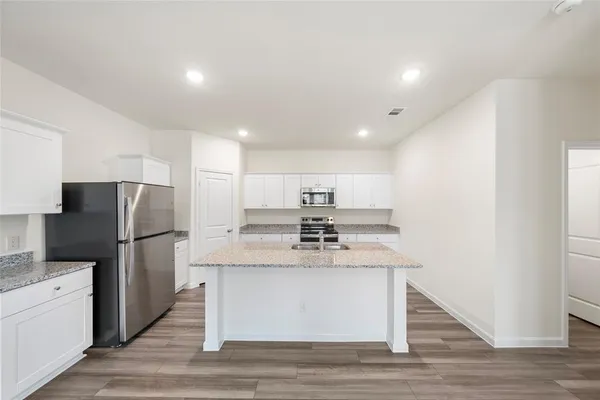 a kitchen with kitchen island stainless steel appliances a refrigerator and a stove top oven