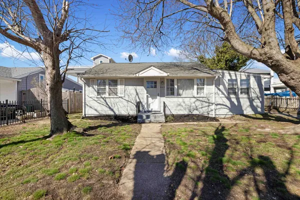 a view of a house with a yard covered with large trees and plants