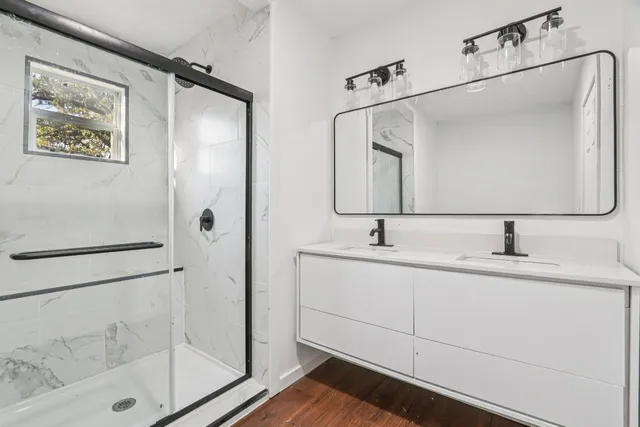 a bathroom with a double vanity sink mirror and shower