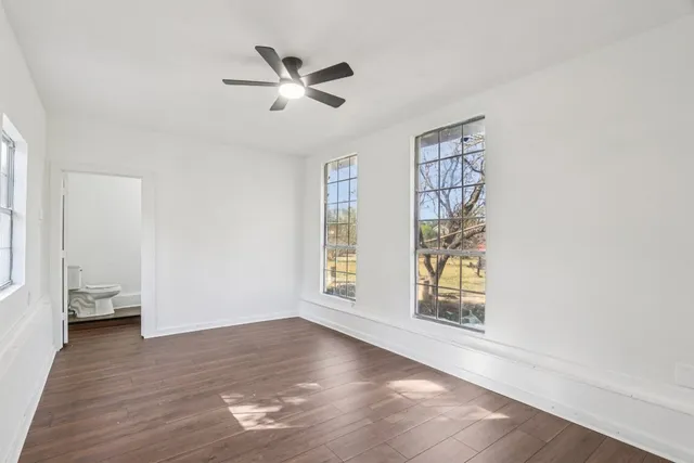 a view of an empty room with a window and wooden floor