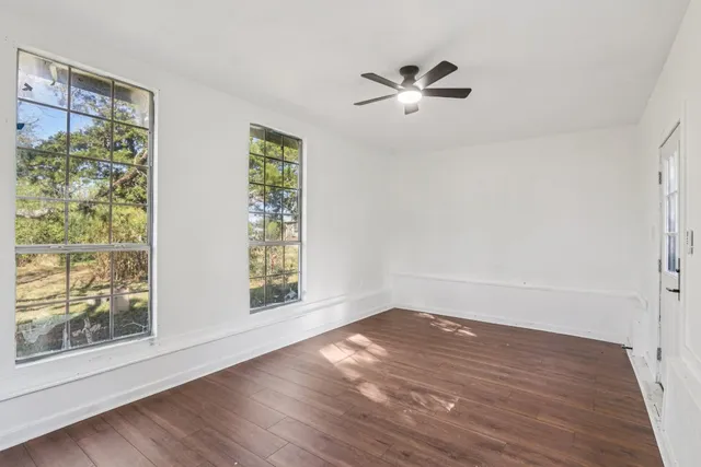 a view of empty room with wooden floor and fan