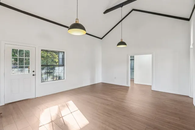 a view of an empty room with a window and wooden floor