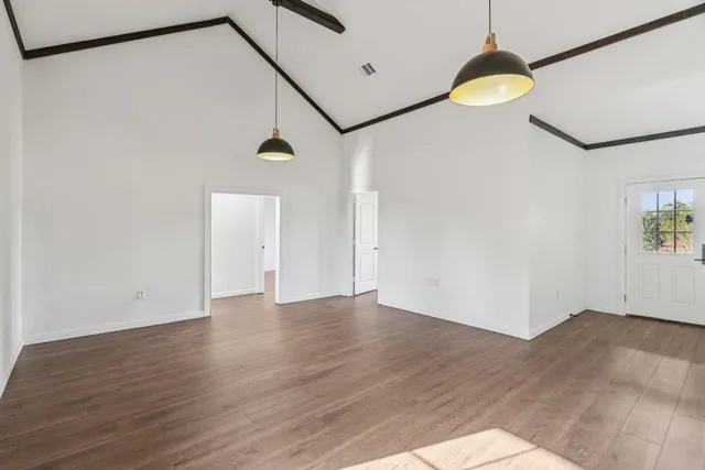 a view of an empty room with wooden floor and a window