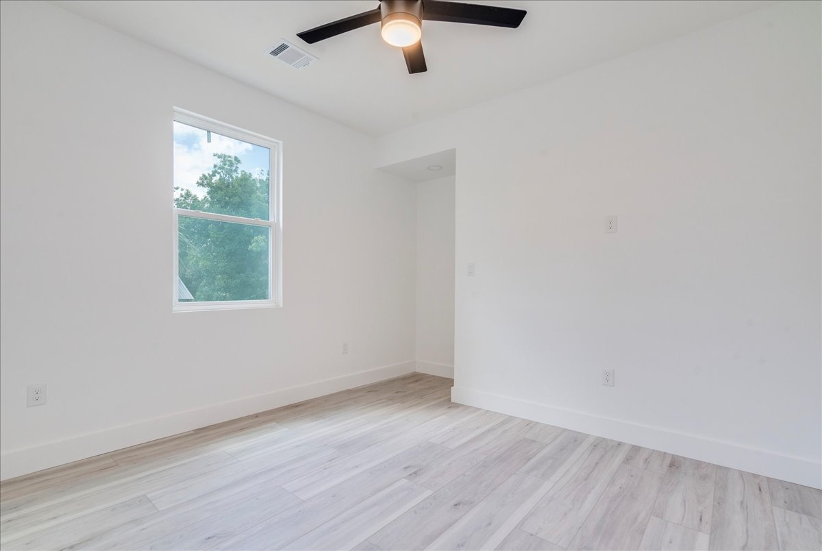 1215 Howard Street Taylor, TX 76574 - Photo 29 of 37 an empty room with wooden floor chandelier fan and windows