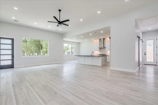 an empty room with wooden floor a ceiling fan and windows
