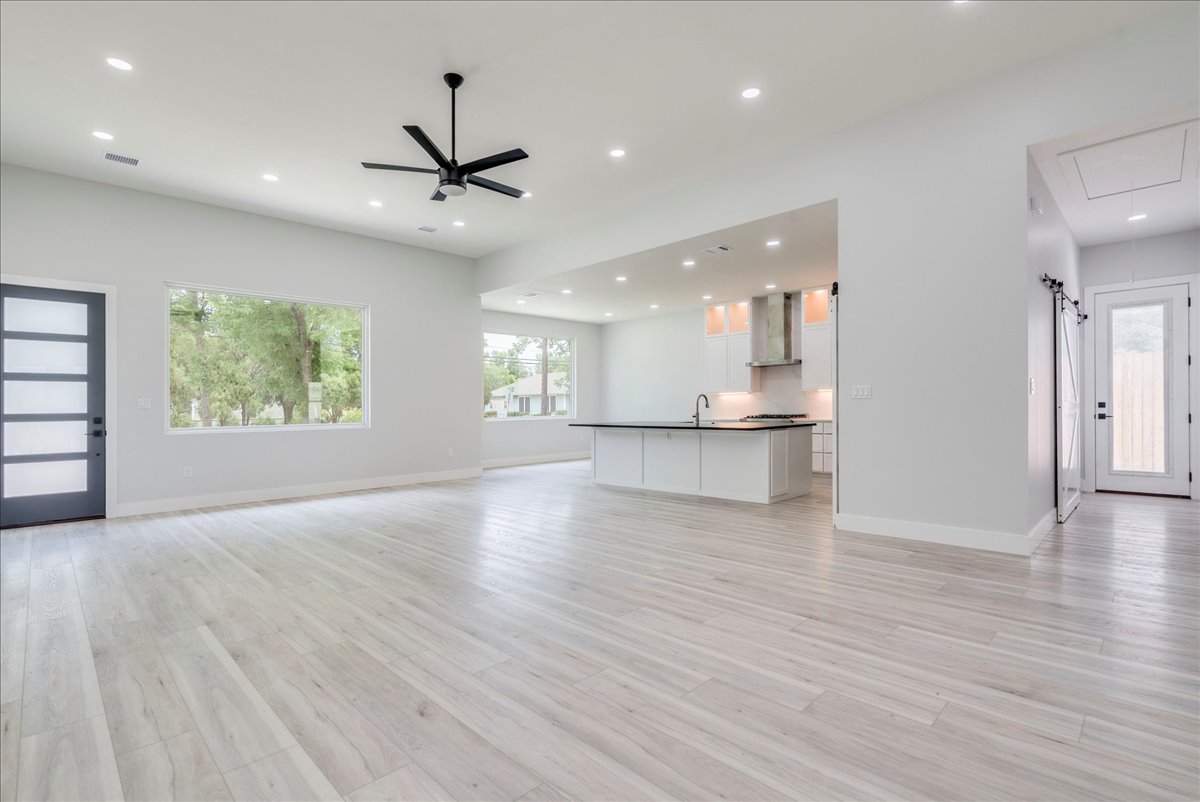 1215 Howard Street Taylor, TX 76574 - Photo 6 of 37 an empty room with wooden floor a ceiling fan and windows