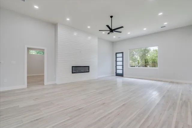 an empty room with wooden floor chandelier and windows