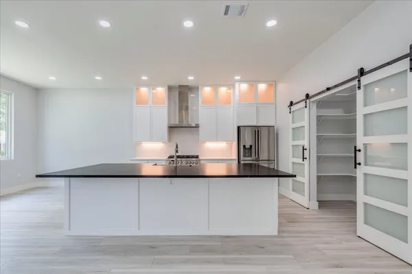 a large kitchen with stainless steel appliances a large counter top a stove and a refrigerator