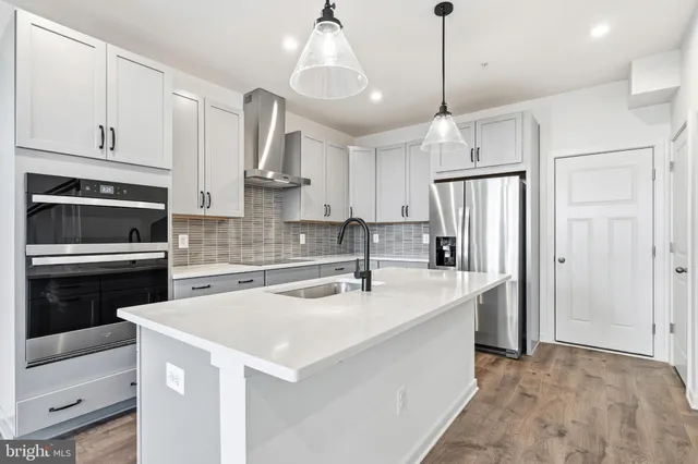 a kitchen with stainless steel appliances granite countertop a sink a stove and a wooden floors