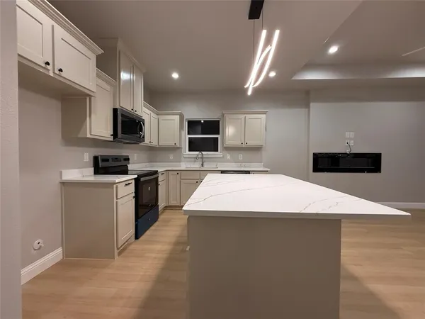 a large kitchen with kitchen island a stove a sink a microwave and a refrigerator