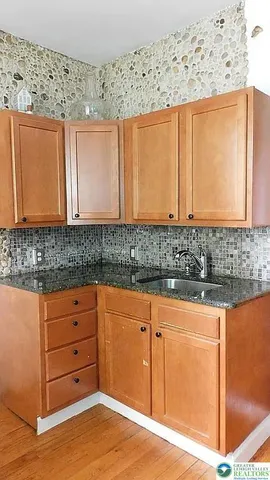 a kitchen with stainless steel appliances granite countertop a sink a stove and a wooden floors