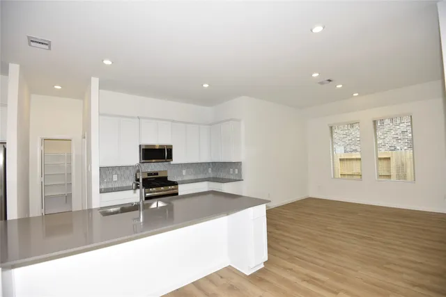 a kitchen with granite countertop a sink cabinets and wooden floor