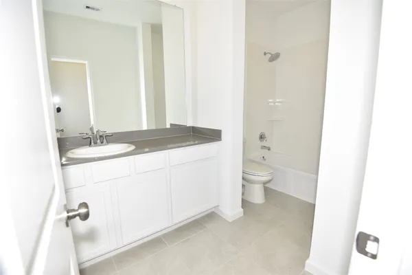 a bathroom with a granite countertop sink a toilet and a mirror