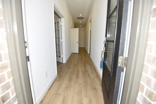 a view of a hallway with wooden floor and staircase