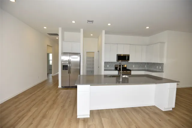a view of a kitchen with kitchen island a sink stainless steel appliances and counter space