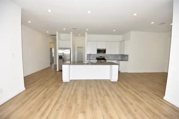 a large kitchen with stainless steel appliances kitchen island a large counter top and a wooden floors