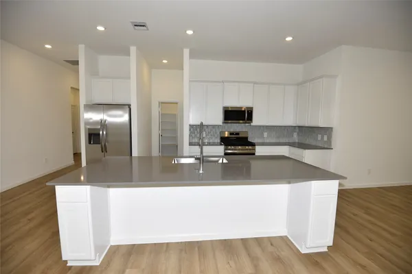 a kitchen with kitchen island a counter top a sink and a stove