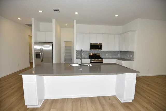 a kitchen with kitchen island a counter top a sink and a stove