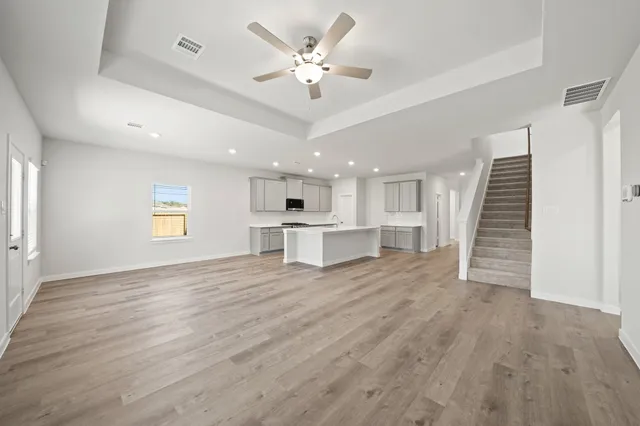 a view of an empty room with wooden floor and a ceiling fan