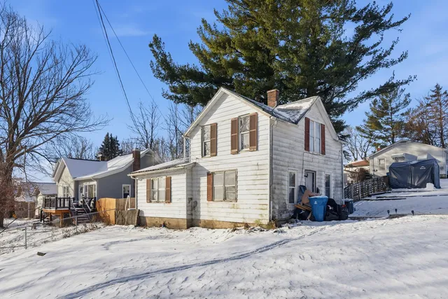a front view of a house with a yard covered with snow