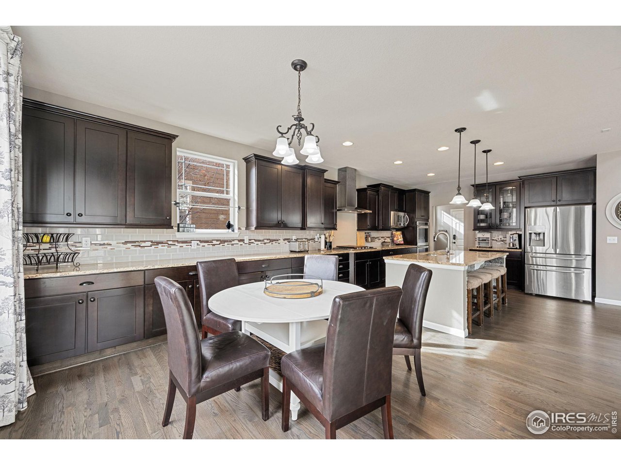 3183 Starry Night Loop Castle Rock, CO 80109 - Photo 11 of 40 a open kitchen with stainless steel appliances kitchen island granite countertop a dining table chairs and white cabinets