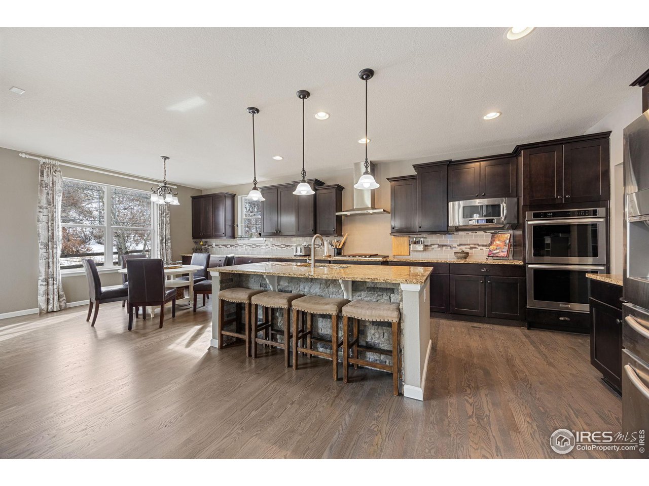 3183 Starry Night Loop Castle Rock, CO 80109 - Photo 8 of 40 a open kitchen with stainless steel appliances granite countertop a stove a refrigerator a kitchen island a dining table and chairs with wooden floor