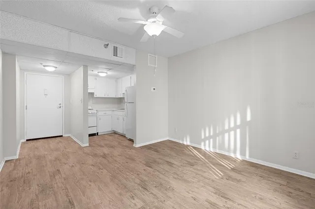 a view of empty room with wooden floor and fan